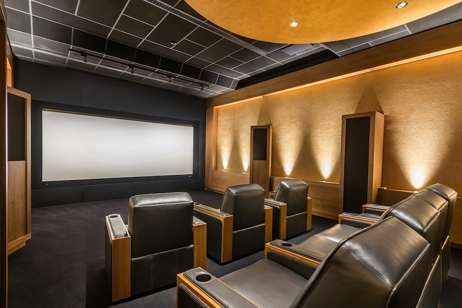 A home theater with black leather seats and a large projection screen.