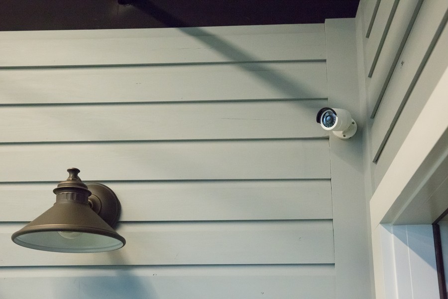 An outdoor security camera mounted above a doorway. 