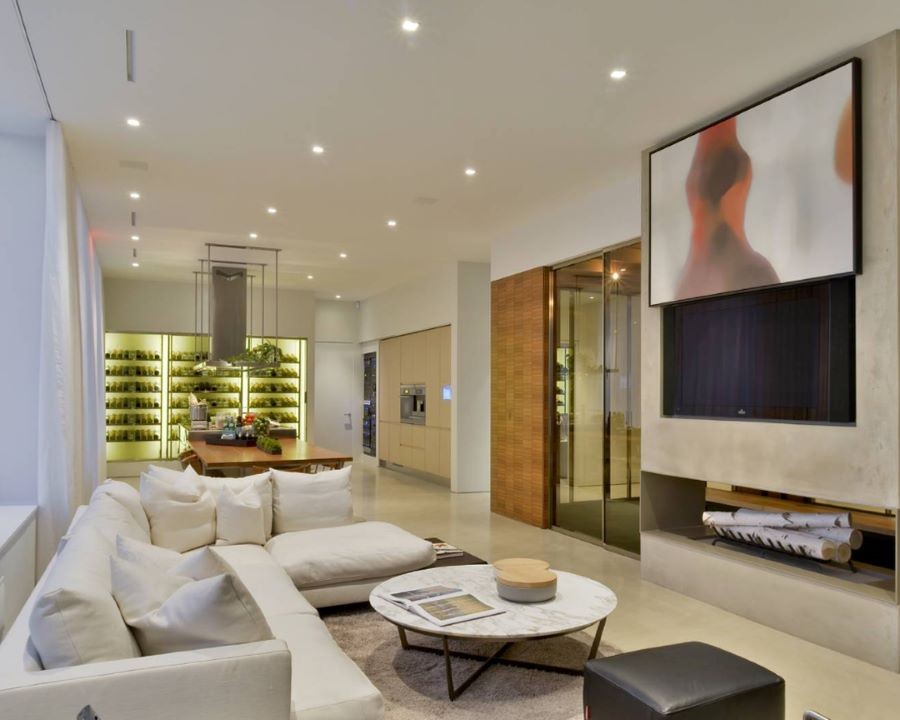 A living area with in-ceiling speakers and a painting rising to reveal a TV.