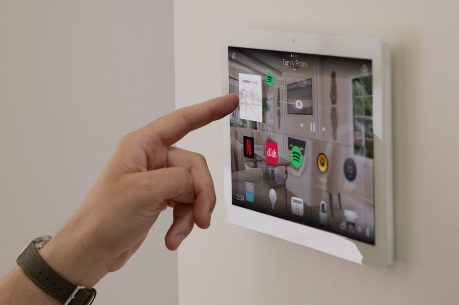 Person’s hand reaching to tap a Control4 smart home control screen.