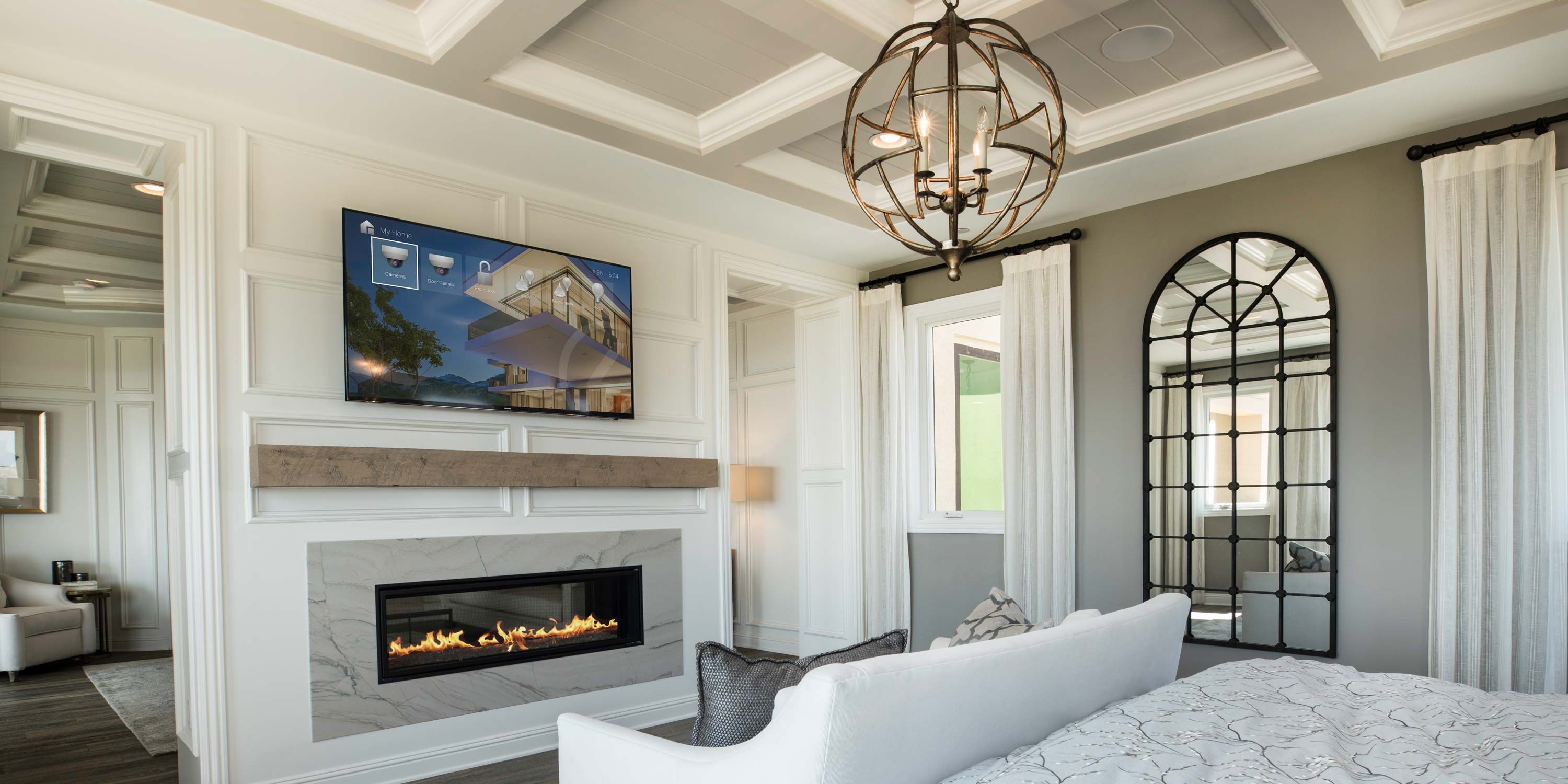 control4 technology in a bedroom with neutral colors and a tv above a fireplace