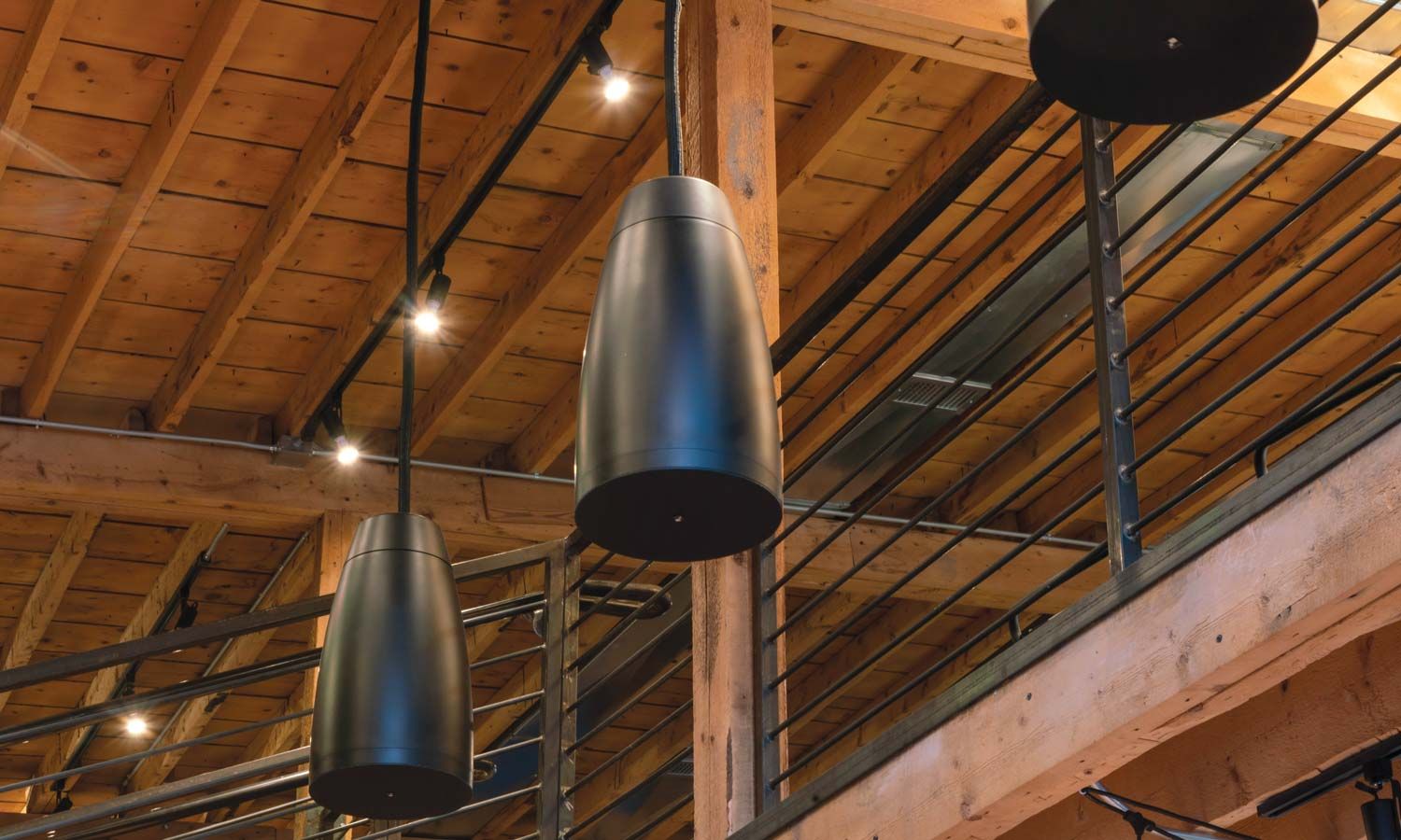 black overhead speakers under a wooden ceiling from sonance