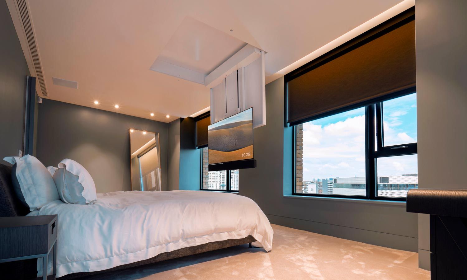 a modern bedroom with an automated tv lowering from the ceiling