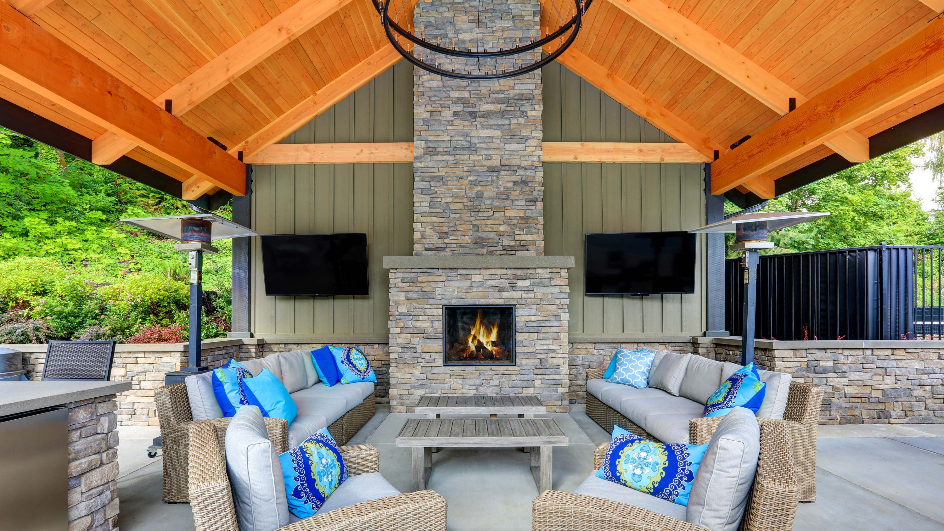 covered porch in a traditional stone porch with a fireplace and two tvs