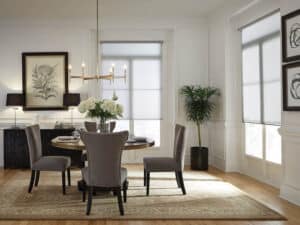 A dining room table next to windows with motorized shades.